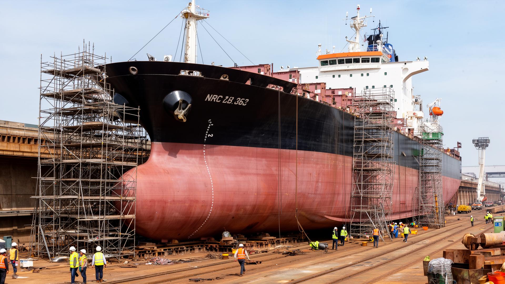 Large vessel in drydock with cranes and engineers